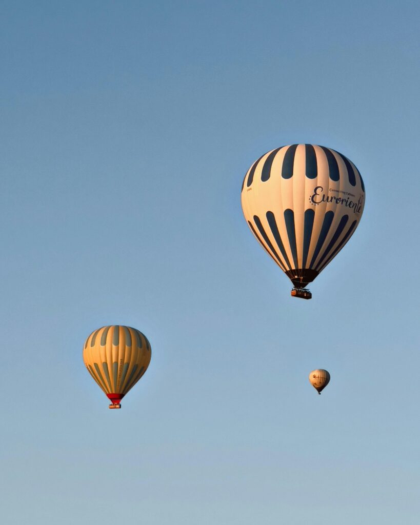 Three hot air balloons soaring peacefully in a clear blue sky.